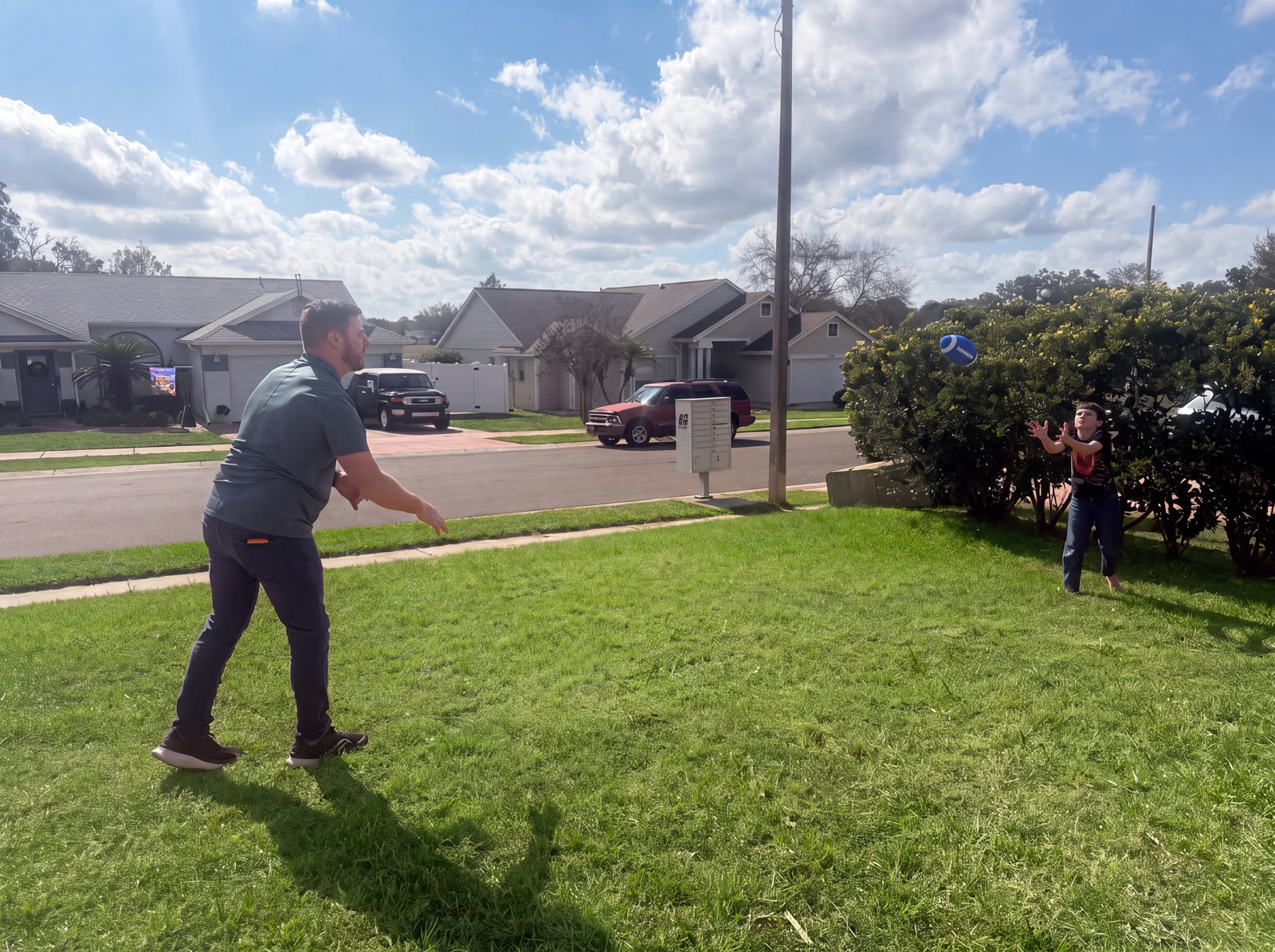A dad and his son playing catch in the front yard between seasons