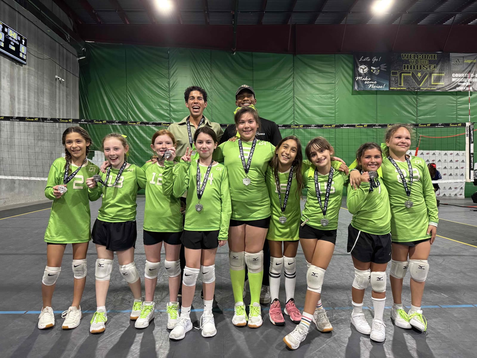 A youth club volleyball team with coaches and medals